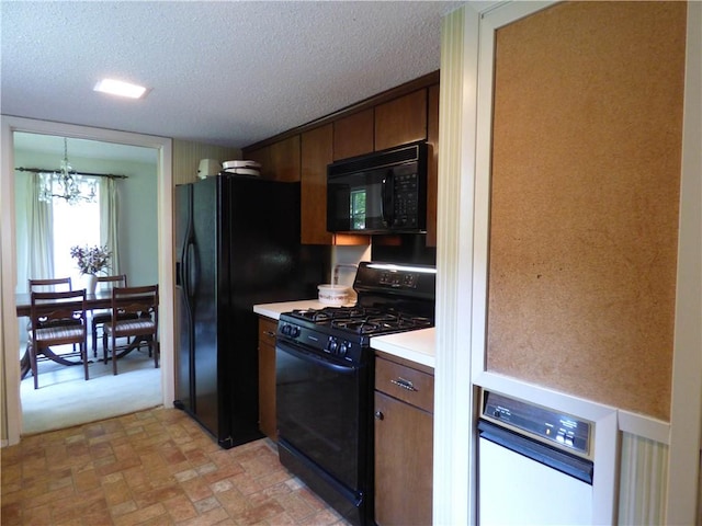 kitchen with black appliances, dark brown cabinets, a textured ceiling, and an inviting chandelier