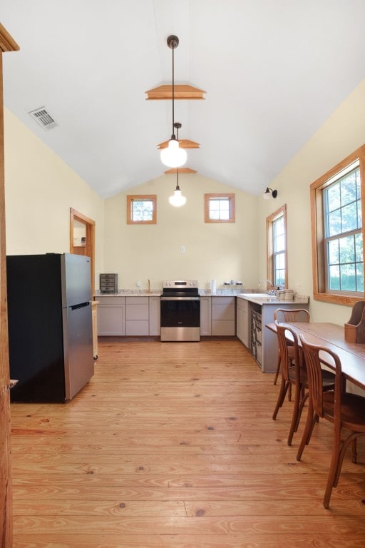 kitchen with light hardwood / wood-style floors, stainless steel appliances, gray cabinetry, hanging light fixtures, and lofted ceiling