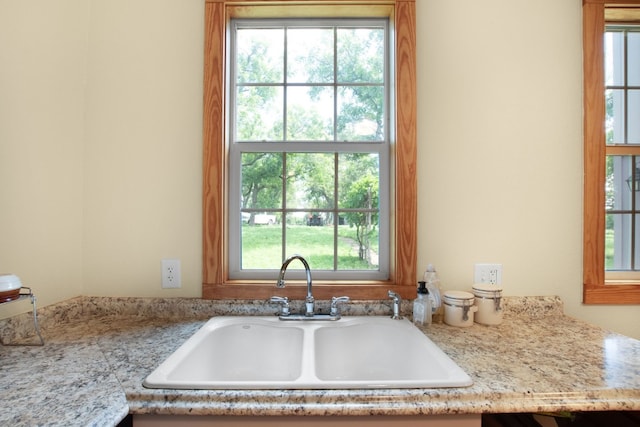 kitchen with sink, a wealth of natural light, and light stone countertops