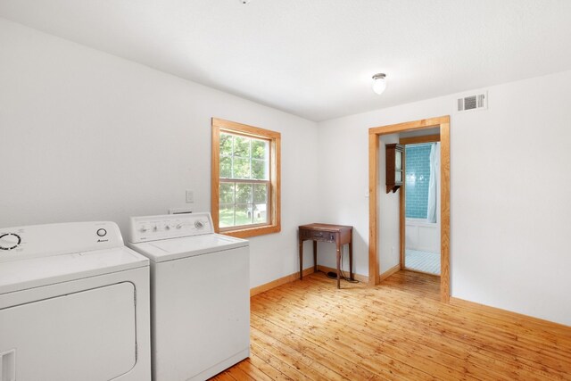 laundry room featuring independent washer and dryer and light hardwood / wood-style flooring