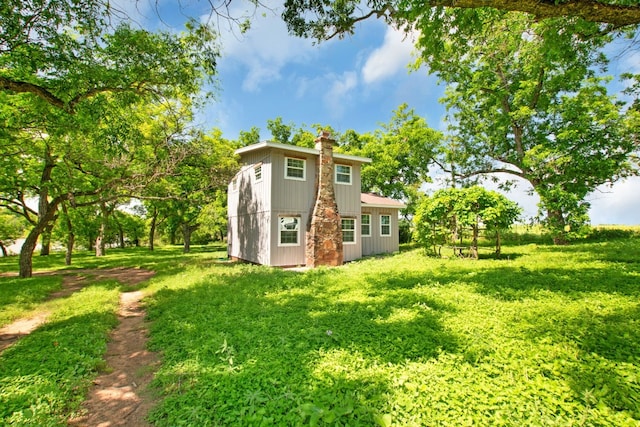 back of house featuring a lawn and a chimney