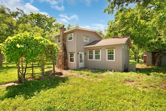 rear view of property with a chimney and a shingled roof