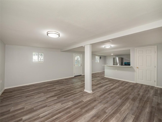 basement featuring stainless steel refrigerator and dark hardwood / wood-style flooring