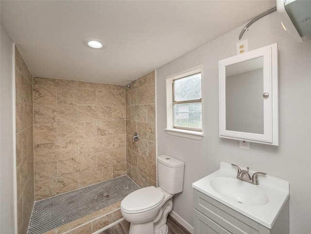 bathroom with vanity, toilet, and tiled shower