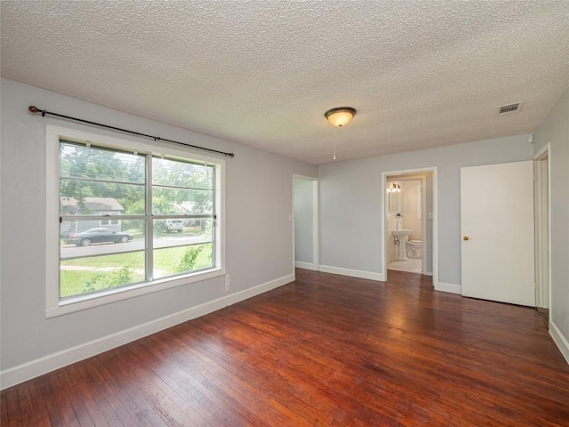 empty room featuring a textured ceiling and dark hardwood / wood-style flooring