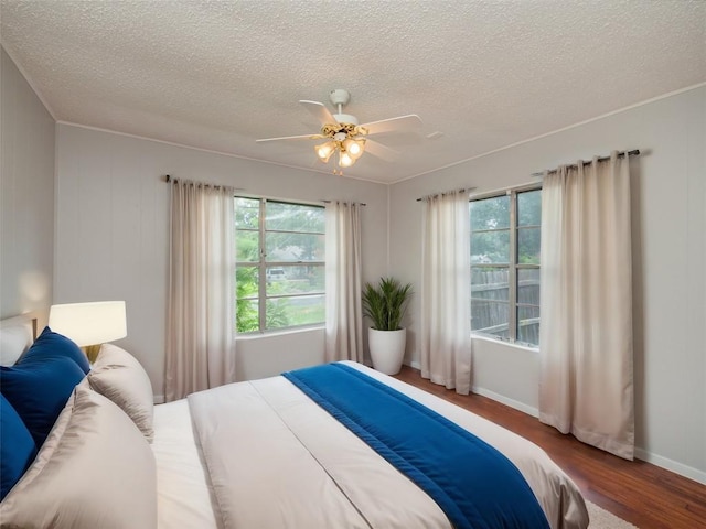 bedroom featuring multiple windows, ceiling fan, hardwood / wood-style floors, and a textured ceiling