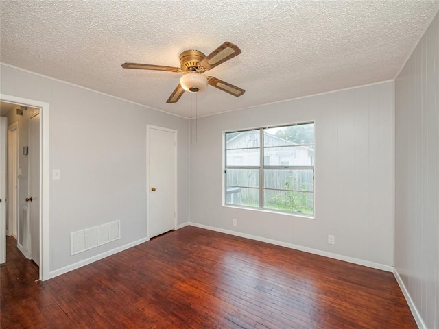 empty room featuring ceiling fan, dark wood-type flooring, and a textured ceiling