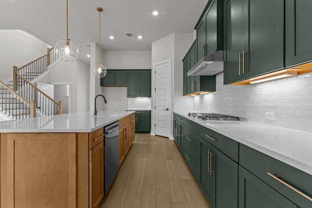 kitchen featuring a center island with sink, stainless steel appliances, exhaust hood, sink, and light hardwood / wood-style floors