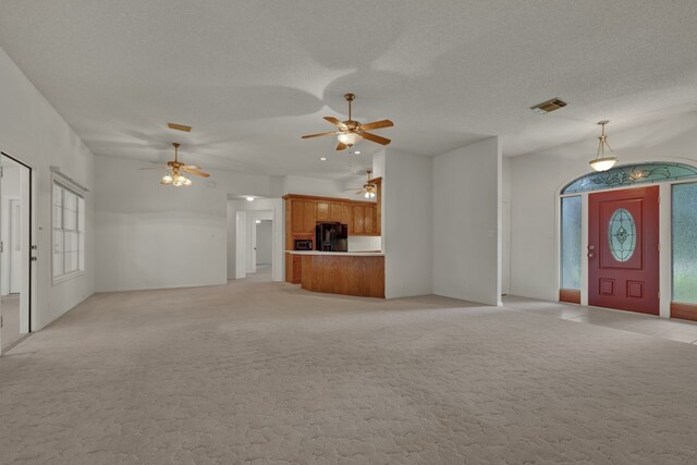 unfurnished living room with light carpet, a textured ceiling, lofted ceiling, and a healthy amount of sunlight