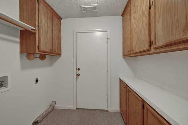 laundry room featuring cabinets, hookup for a washing machine, a textured ceiling, and electric dryer hookup