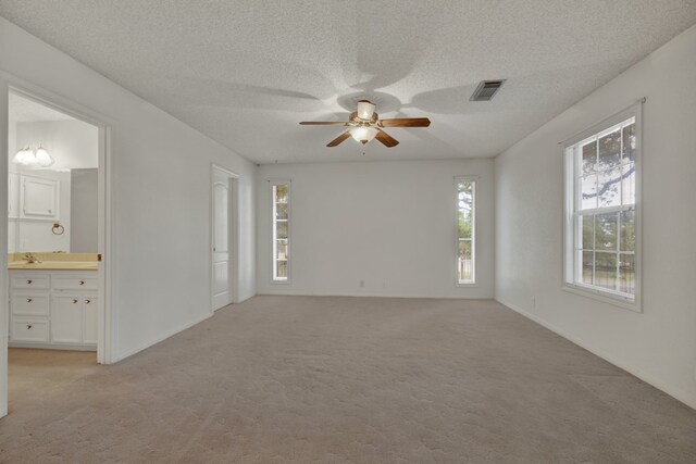 spare room featuring a textured ceiling, light colored carpet, and ceiling fan