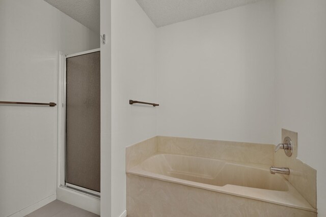 bathroom with tile patterned flooring, separate shower and tub, and a textured ceiling