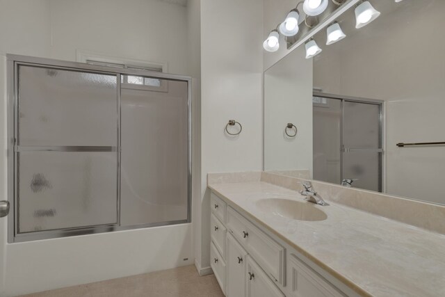 bathroom with tile patterned floors, vanity, and enclosed tub / shower combo