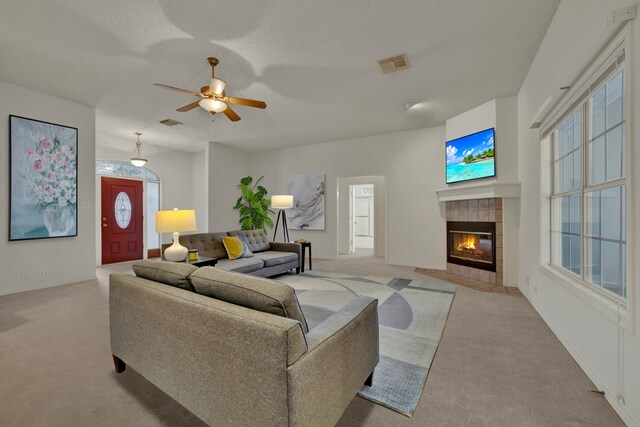 carpeted living room with ceiling fan, a fireplace, and a textured ceiling