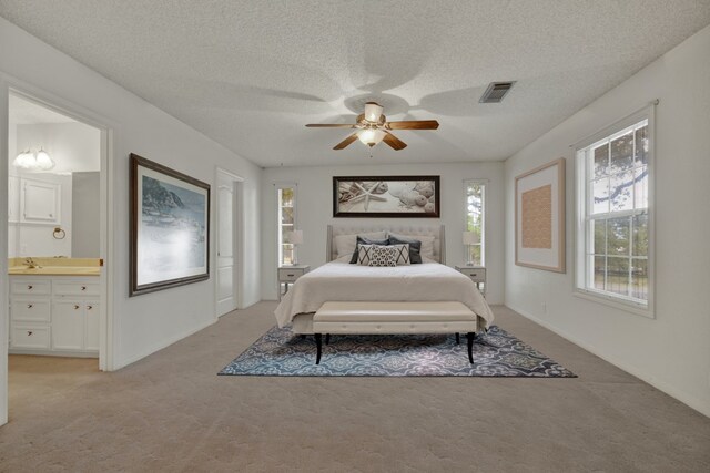 bedroom with a textured ceiling, ceiling fan, light colored carpet, and ensuite bathroom