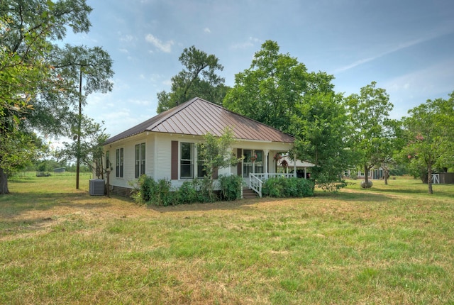 view of front facade featuring covered porch, central AC unit, and a front yard