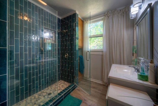 bathroom with hardwood / wood-style floors, an enclosed shower, a textured ceiling, and vanity