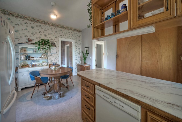 kitchen featuring white appliances, light tile patterned floors, and light stone counters