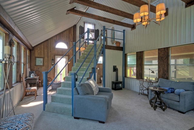 living room featuring high vaulted ceiling, wood walls, a notable chandelier, and plenty of natural light