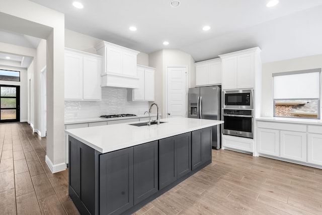 kitchen with stainless steel appliances, a kitchen island with sink, white cabinets, and sink