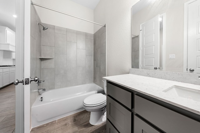 full bathroom with vanity, hardwood / wood-style floors, tiled shower / bath combo, and toilet