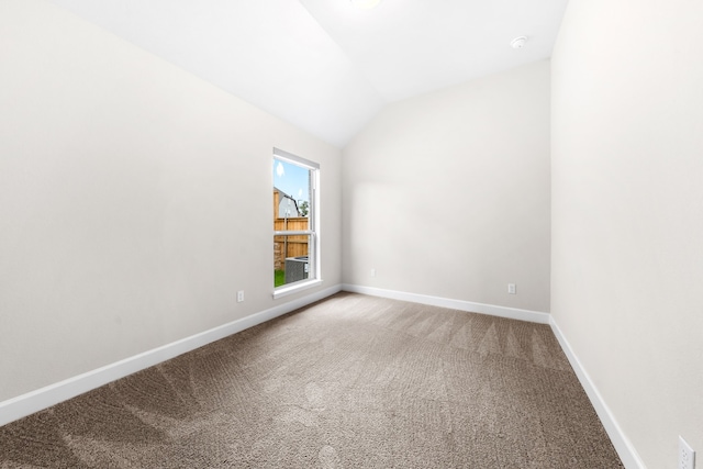 empty room with vaulted ceiling and carpet floors