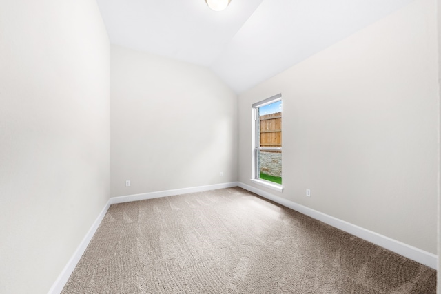 carpeted spare room featuring vaulted ceiling