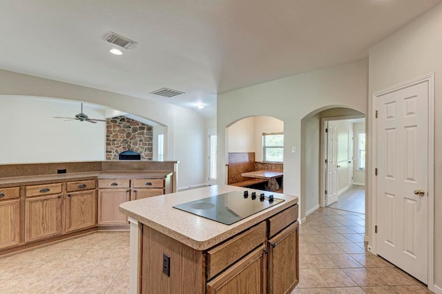 kitchen with light tile patterned flooring, ceiling fan, black electric stovetop, and a kitchen island