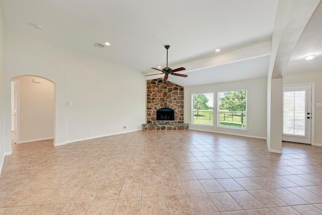 unfurnished living room with ceiling fan, a stone fireplace, vaulted ceiling, and light tile patterned floors