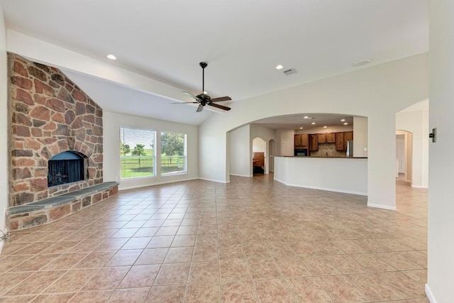 unfurnished living room with a fireplace, light tile patterned flooring, ceiling fan, and vaulted ceiling