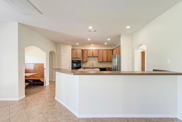 kitchen featuring stainless steel refrigerator, sink, oven, decorative backsplash, and light tile patterned floors