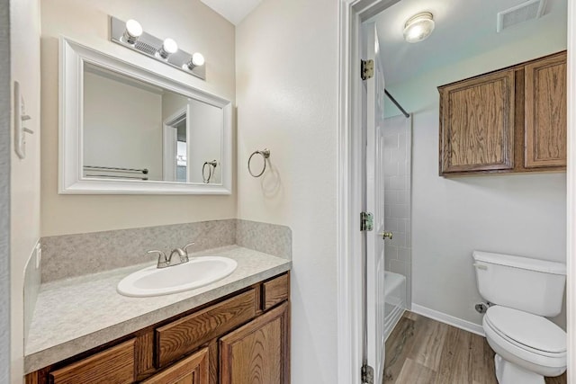 full bathroom featuring hardwood / wood-style flooring,  shower combination, vanity, and toilet