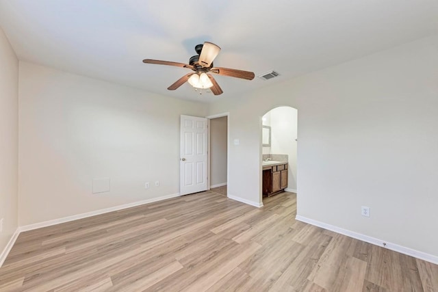 unfurnished bedroom featuring ceiling fan, connected bathroom, sink, and light wood-type flooring