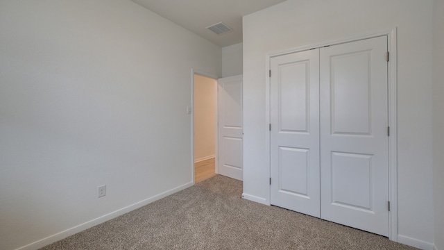 unfurnished bedroom with light carpet and a closet