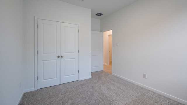 unfurnished bedroom featuring light colored carpet and a closet