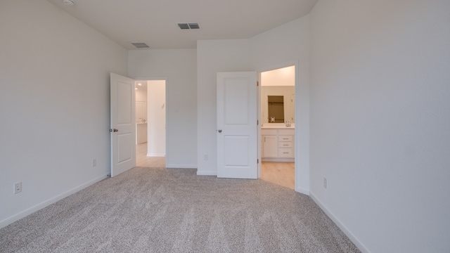 unfurnished bedroom featuring light colored carpet and connected bathroom