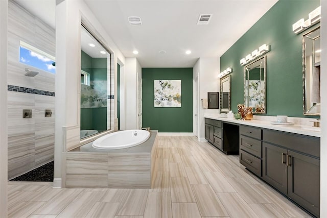 bathroom featuring vanity and independent shower and bath