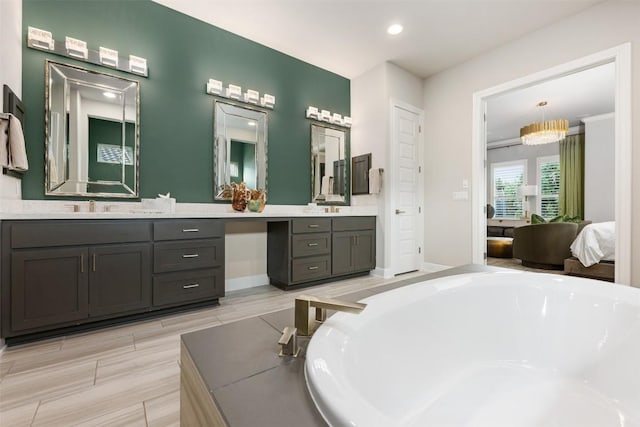 bathroom with a chandelier, vanity, and a relaxing tiled tub