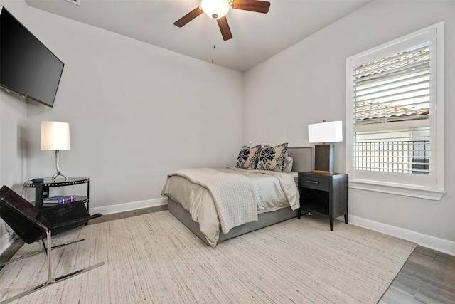 bedroom featuring hardwood / wood-style flooring, ceiling fan, and multiple windows