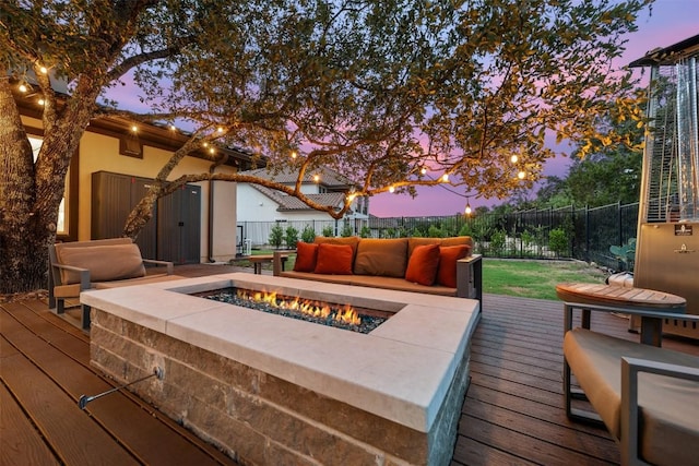 deck at dusk featuring an outdoor living space with a fire pit