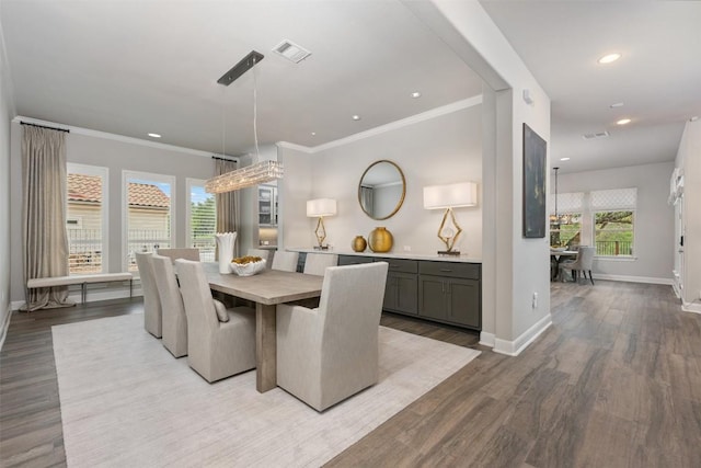 dining room with ornamental molding and light hardwood / wood-style flooring