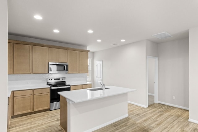 kitchen with light wood-type flooring, sink, a kitchen island with sink, and appliances with stainless steel finishes