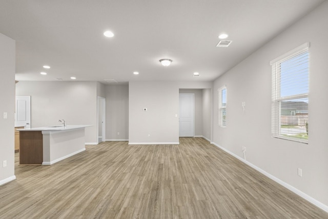 unfurnished living room featuring sink and light hardwood / wood-style floors