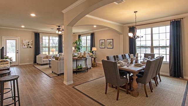 dining room featuring ceiling fan with notable chandelier, crown molding, and dark wood-type flooring