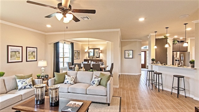 living room with ornamental molding, ceiling fan with notable chandelier, and light wood-type flooring