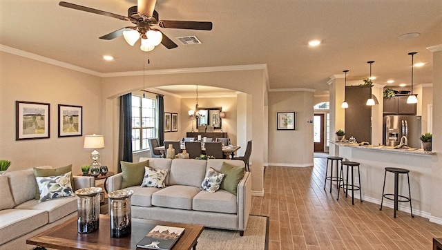 living room featuring ornamental molding, ceiling fan with notable chandelier, light wood-type flooring, and sink