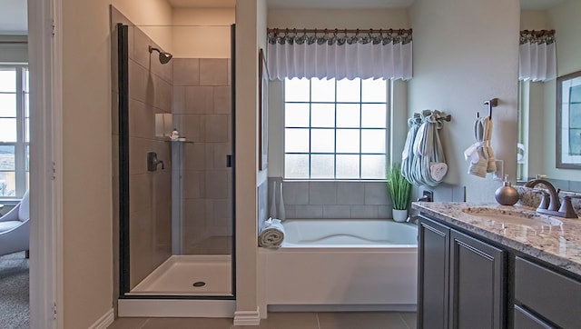 bathroom featuring plus walk in shower, tile flooring, a wealth of natural light, and vanity