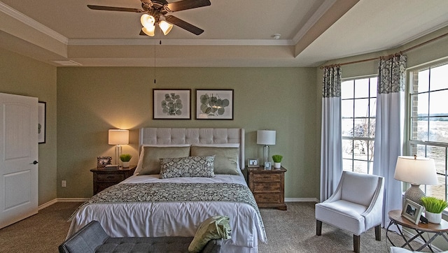 carpeted bedroom featuring ceiling fan, a raised ceiling, and ornamental molding