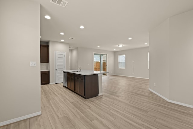 kitchen featuring dishwasher, sink, a center island with sink, dark brown cabinets, and light wood-type flooring