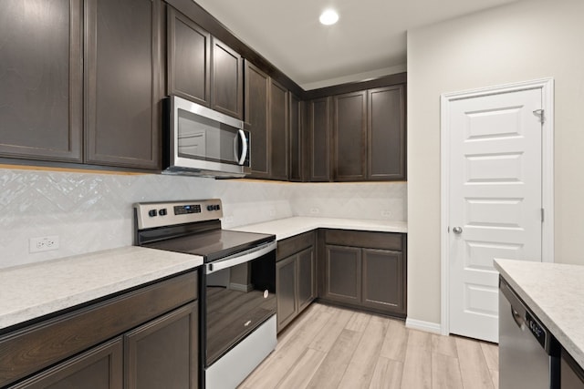 kitchen featuring backsplash, dark brown cabinetry, light hardwood / wood-style floors, and appliances with stainless steel finishes